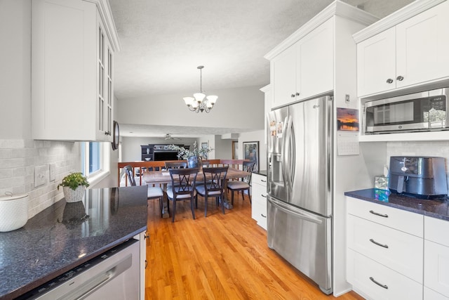 kitchen with backsplash, vaulted ceiling, stainless steel appliances, an inviting chandelier, and white cabinetry