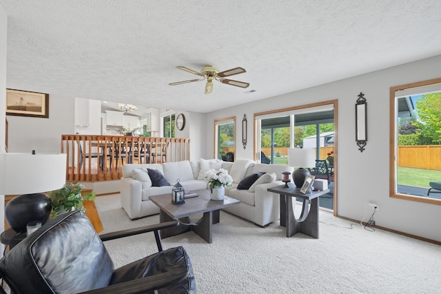 living room with a ceiling fan, light colored carpet, and a textured ceiling