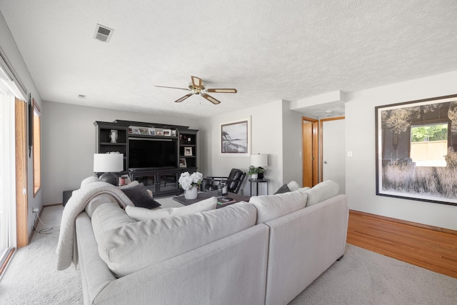 living area featuring visible vents, wood finished floors, a textured ceiling, and ceiling fan