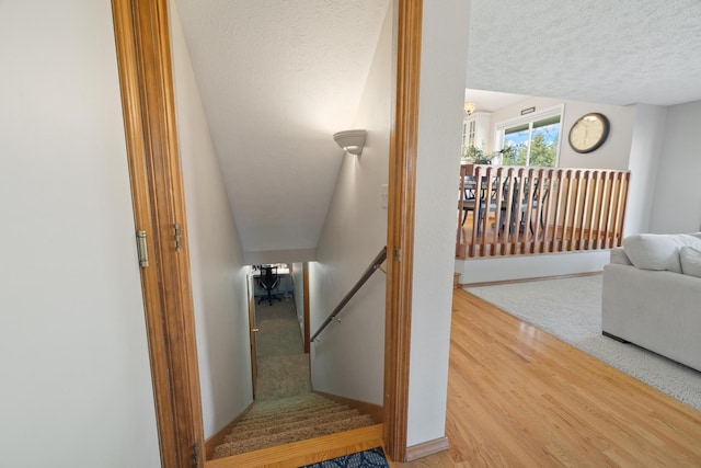 stairway with a textured ceiling, baseboards, and wood finished floors