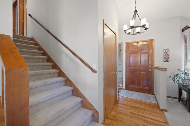 foyer with an inviting chandelier, stairway, baseboards, and light wood-type flooring