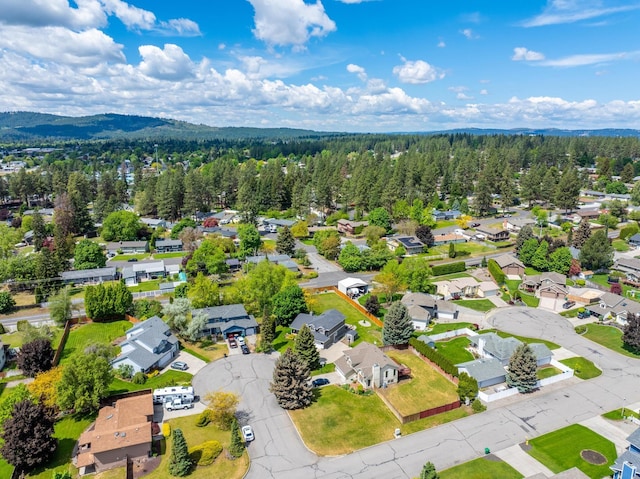 drone / aerial view featuring a mountain view, a view of trees, and a residential view