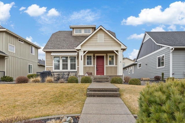 view of front of house with a front yard, board and batten siding, and roof with shingles