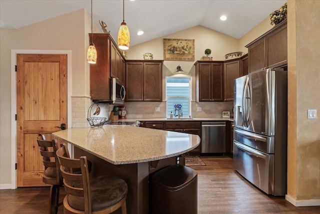 kitchen with a breakfast bar, a sink, stainless steel appliances, a peninsula, and vaulted ceiling