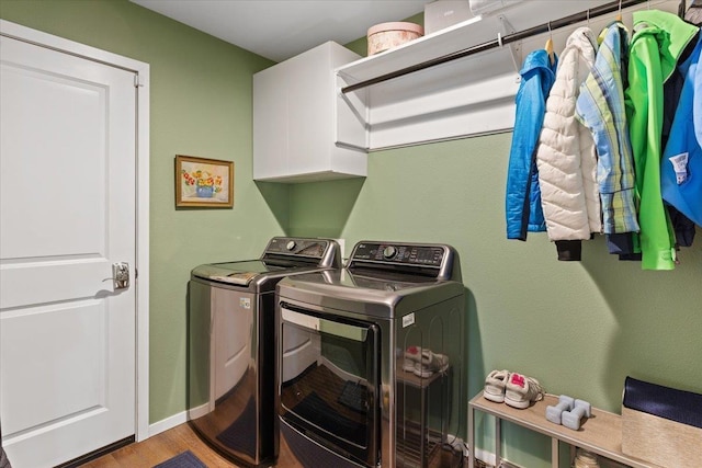 washroom with wood finished floors, cabinet space, and washer and clothes dryer