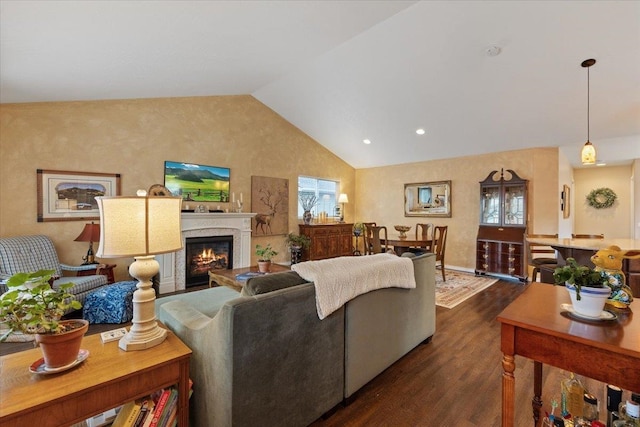 living area featuring a wealth of natural light, a glass covered fireplace, lofted ceiling, and dark wood-style flooring