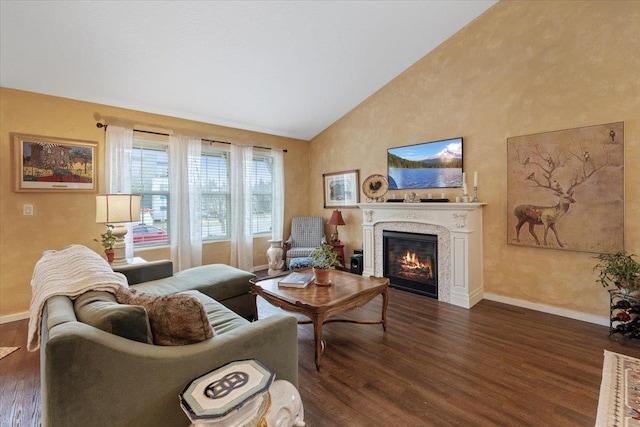 living area featuring dark wood-style floors, a glass covered fireplace, high vaulted ceiling, and baseboards