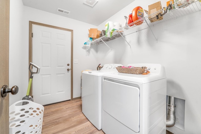 washroom with laundry area, light wood-style flooring, visible vents, and separate washer and dryer