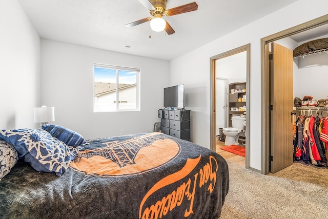 bedroom featuring visible vents, connected bathroom, a walk in closet, light colored carpet, and a ceiling fan