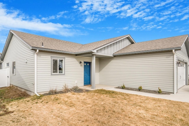 single story home featuring a garage, a front yard, roof with shingles, and driveway