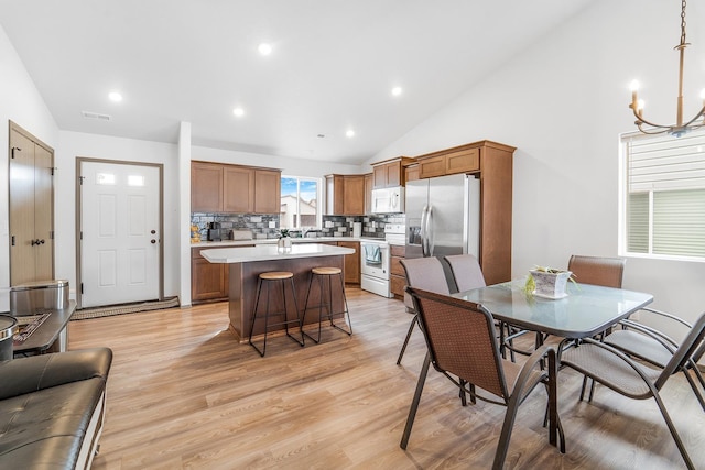 dining room with visible vents, light wood finished floors, high vaulted ceiling, an inviting chandelier, and recessed lighting