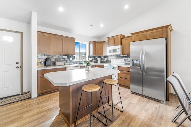 kitchen featuring white appliances, a breakfast bar area, light countertops, and light wood-type flooring