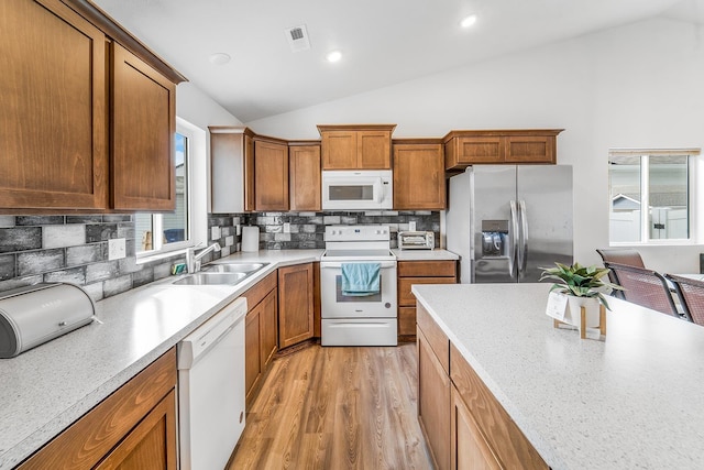 kitchen with a sink, white appliances, lofted ceiling, and light countertops