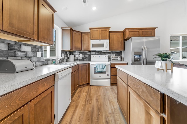 kitchen featuring visible vents, a sink, white appliances, light countertops, and vaulted ceiling