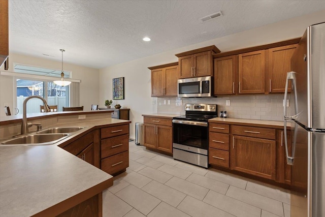 kitchen with visible vents, a sink, stainless steel appliances, brown cabinets, and backsplash