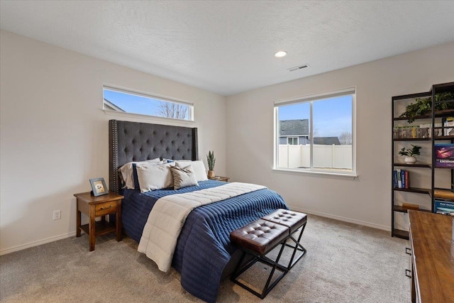 bedroom featuring visible vents, light colored carpet, a textured ceiling, and baseboards