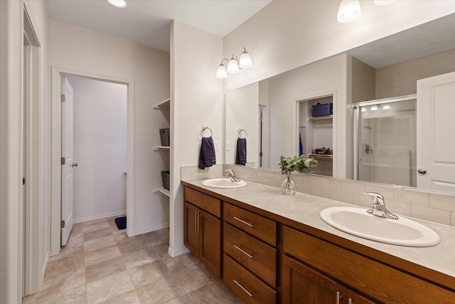 full bath with a sink, backsplash, double vanity, and a shower stall