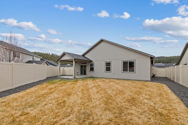 rear view of house featuring a yard, a fenced backyard, and a patio