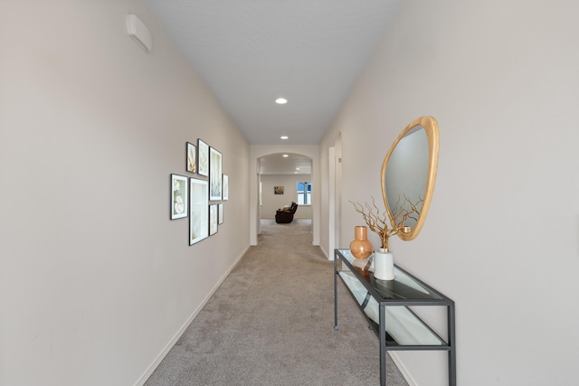 hallway with recessed lighting, baseboards, arched walkways, and light carpet