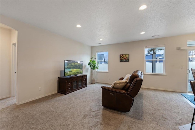 living room with carpet, baseboards, recessed lighting, arched walkways, and a textured ceiling