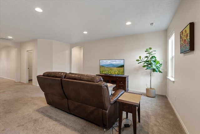 living area with recessed lighting, light colored carpet, arched walkways, and baseboards