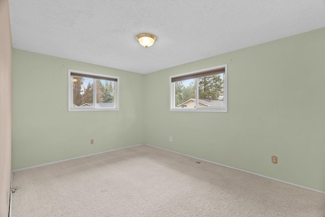 carpeted empty room with visible vents, a textured ceiling, and baseboards