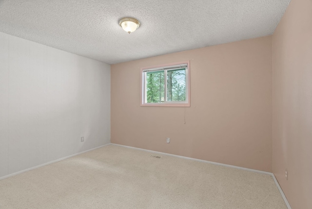 carpeted empty room with visible vents, baseboards, and a textured ceiling