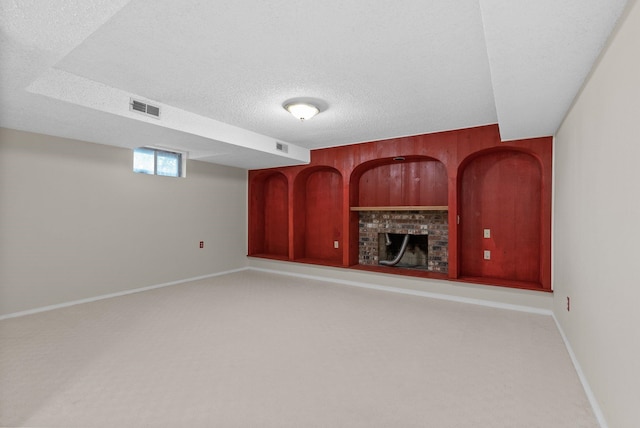 unfurnished living room with visible vents, a brick fireplace, wood walls, carpet flooring, and a textured ceiling