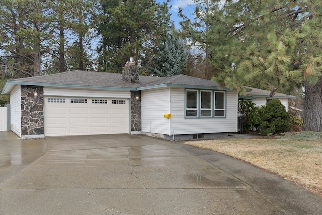 ranch-style house featuring a chimney, an attached garage, concrete driveway, and roof with shingles