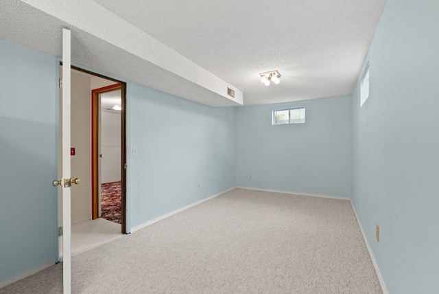 below grade area with carpet flooring, a textured ceiling, and baseboards