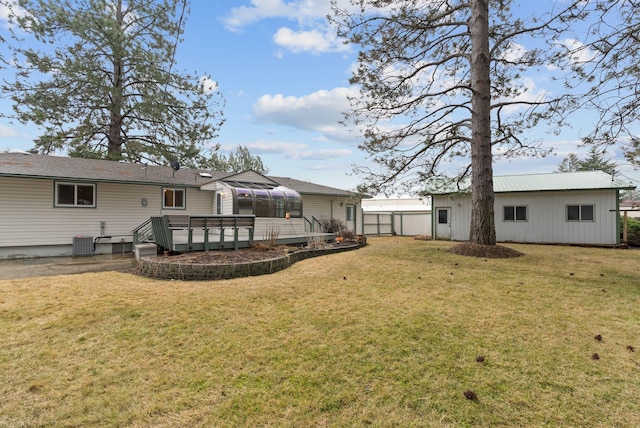 rear view of property with a yard, a wooden deck, central AC unit, and an outdoor structure