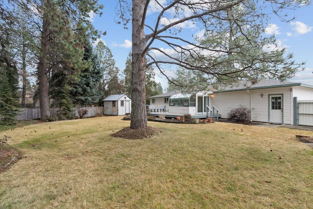 view of yard with a storage unit, a sunroom, an outbuilding, and fence