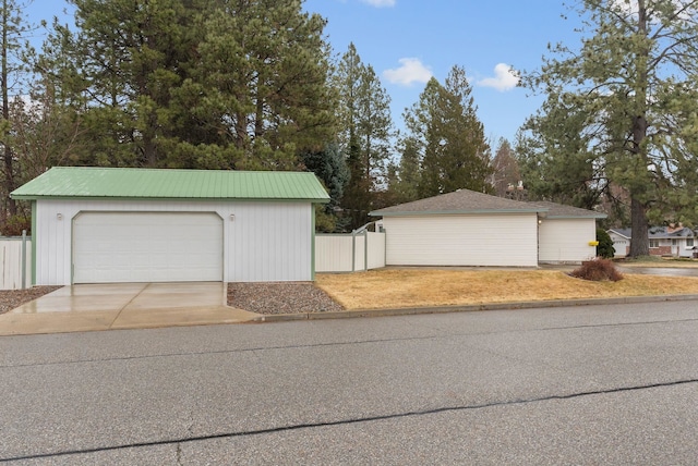 garage with concrete driveway and fence