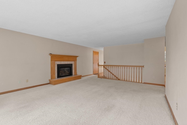 unfurnished living room with carpet flooring, baseboards, and a textured ceiling