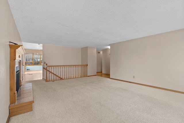 empty room with carpet, baseboards, and a textured ceiling