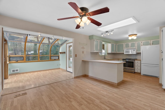 kitchen featuring white appliances, a peninsula, visible vents, and a sink