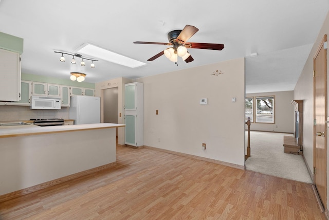 kitchen with light wood-style flooring, white appliances, a peninsula, a skylight, and ceiling fan