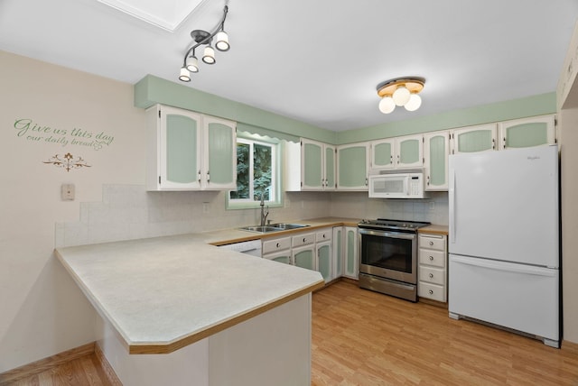 kitchen with backsplash, light wood-style flooring, a peninsula, white appliances, and a sink