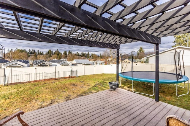 wooden deck with a fenced backyard, a pergola, a trampoline, a lawn, and a residential view