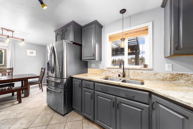 kitchen with light tile patterned floors, stainless steel fridge, a wealth of natural light, and a sink