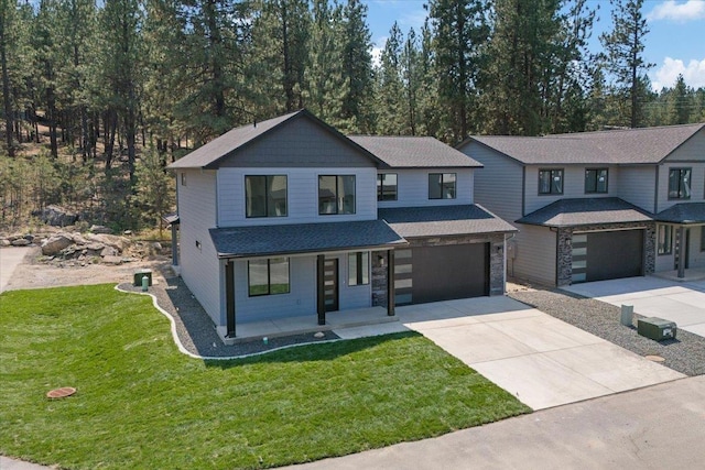 view of front of property with a front lawn, covered porch, a garage, stone siding, and driveway