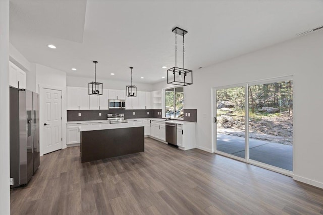 kitchen featuring tasteful backsplash, visible vents, a kitchen island, appliances with stainless steel finishes, and dark wood-style floors