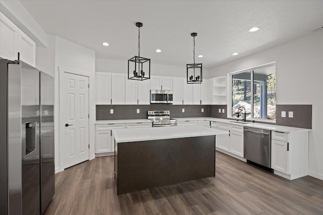 kitchen with dark wood-style flooring, a sink, white cabinets, appliances with stainless steel finishes, and pendant lighting