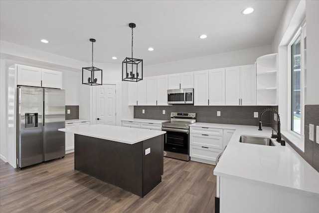 kitchen featuring a sink, a kitchen island, dark wood finished floors, appliances with stainless steel finishes, and open shelves