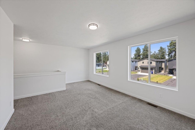 carpeted spare room with visible vents and baseboards