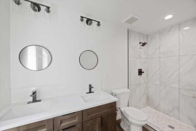 full bath featuring a sink, visible vents, tiled shower, and toilet