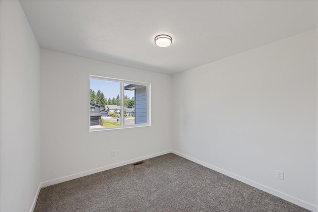 carpeted spare room featuring visible vents and baseboards