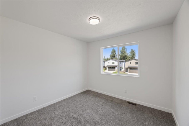 spare room featuring carpet flooring, baseboards, visible vents, and a textured ceiling