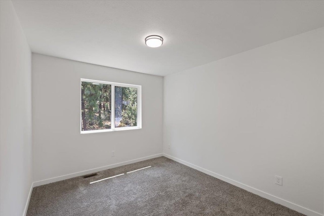 carpeted empty room featuring visible vents and baseboards