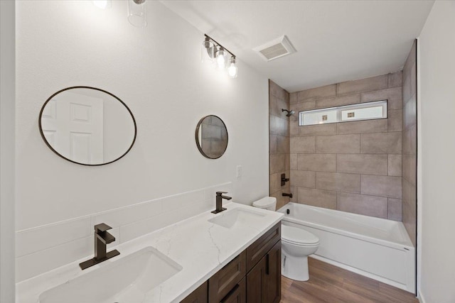 bathroom with toilet, wood finished floors, visible vents, and a sink